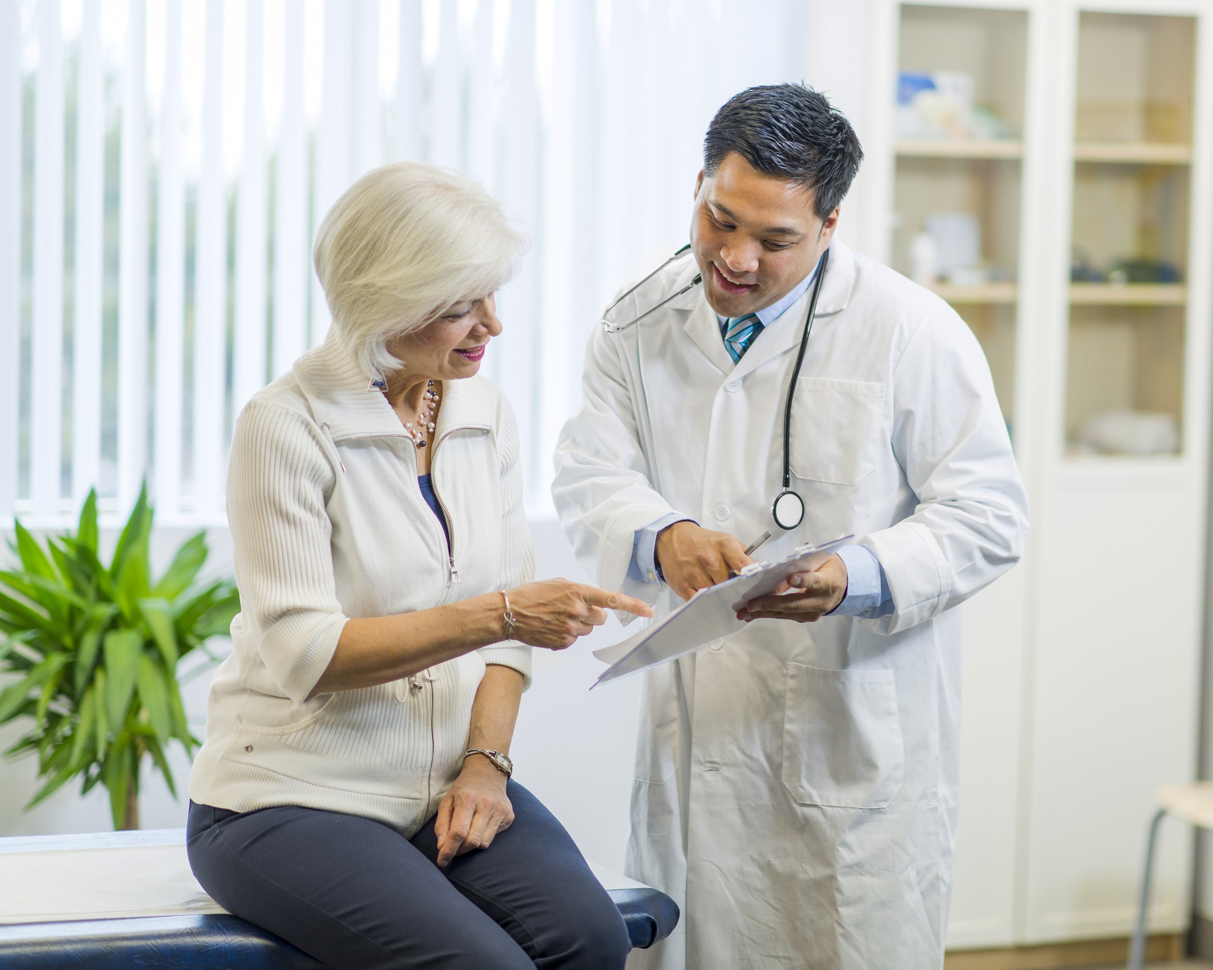middle-aged woman in doctor office going over with doctor