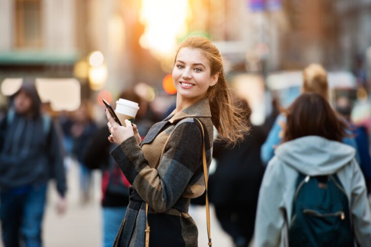 smiling businesswoman walking on busy city street from work