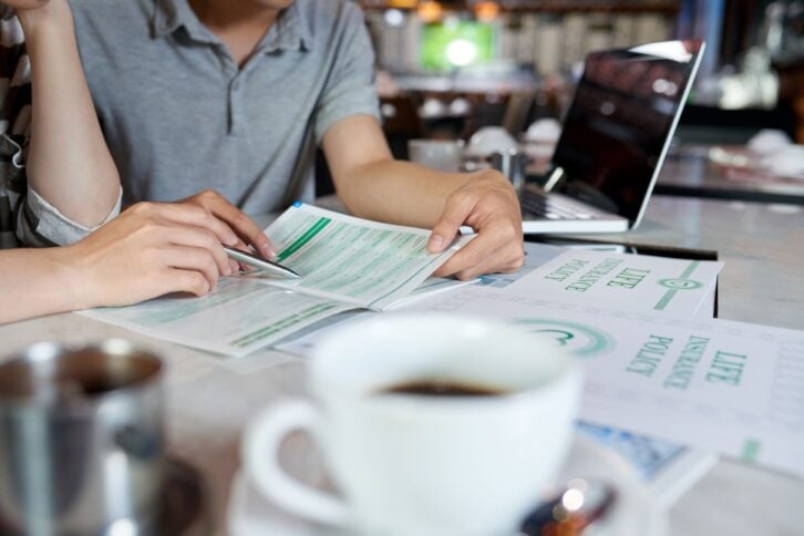 couple at coffee shop studying life insurance brochure