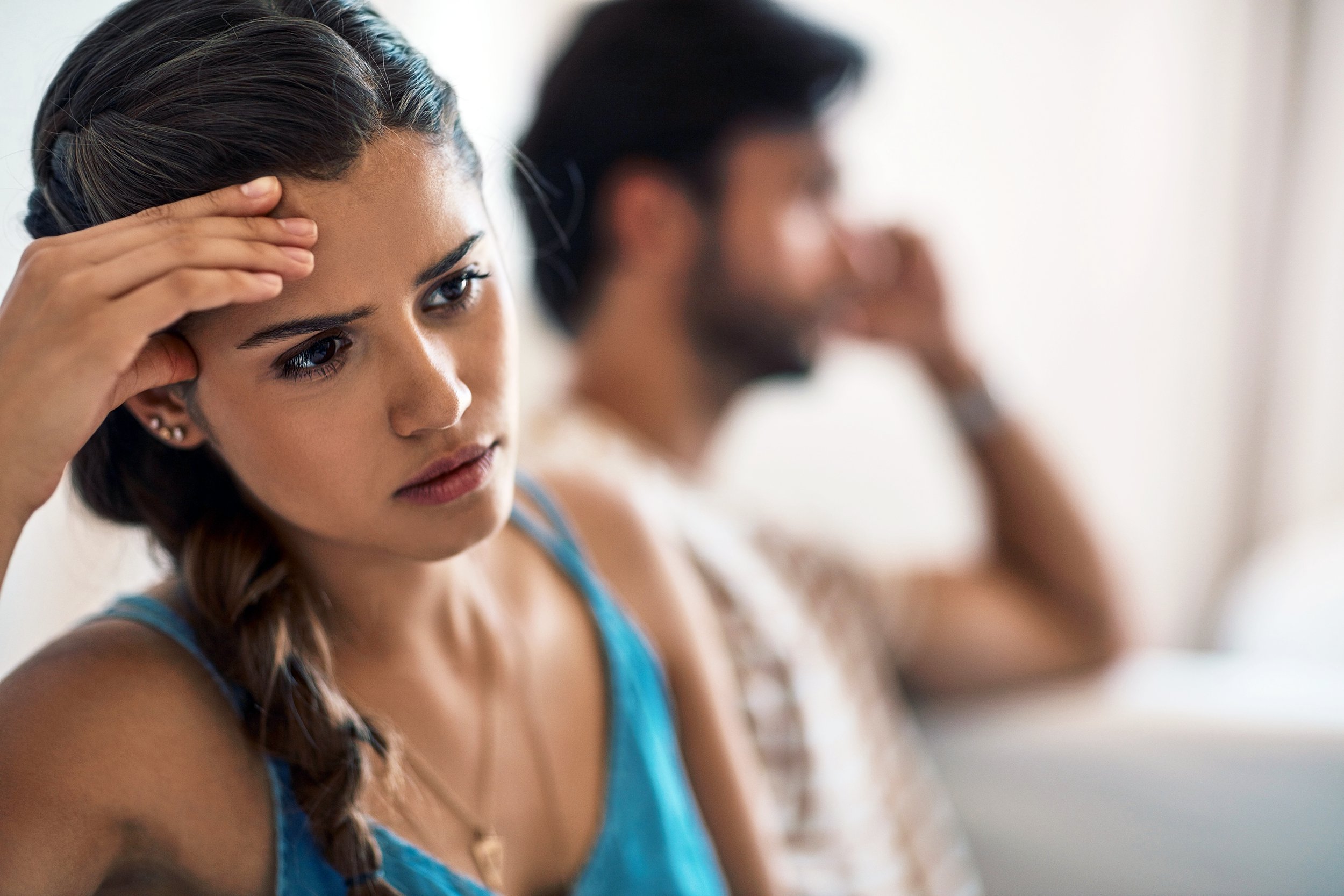 Couple sitting on the couch looking upset with woman in foreground