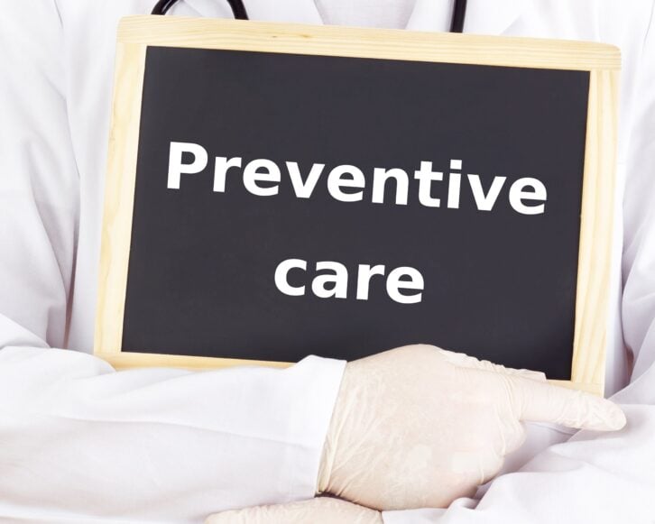 doctor holding blackboard with 'Preventive Care' on it
