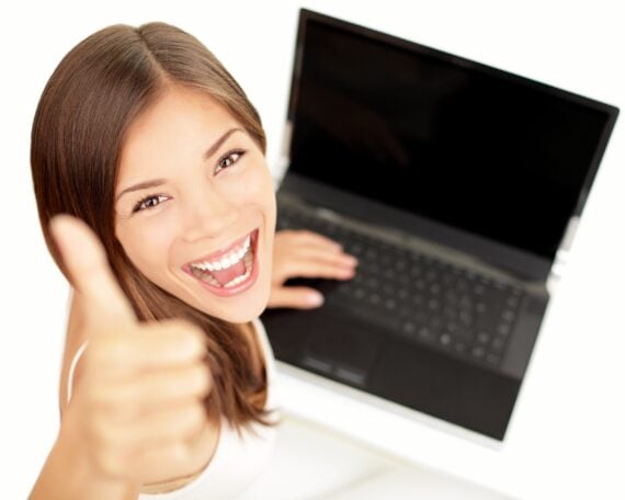 happy woman giving thumbs up sitting at laptop with excited face expression