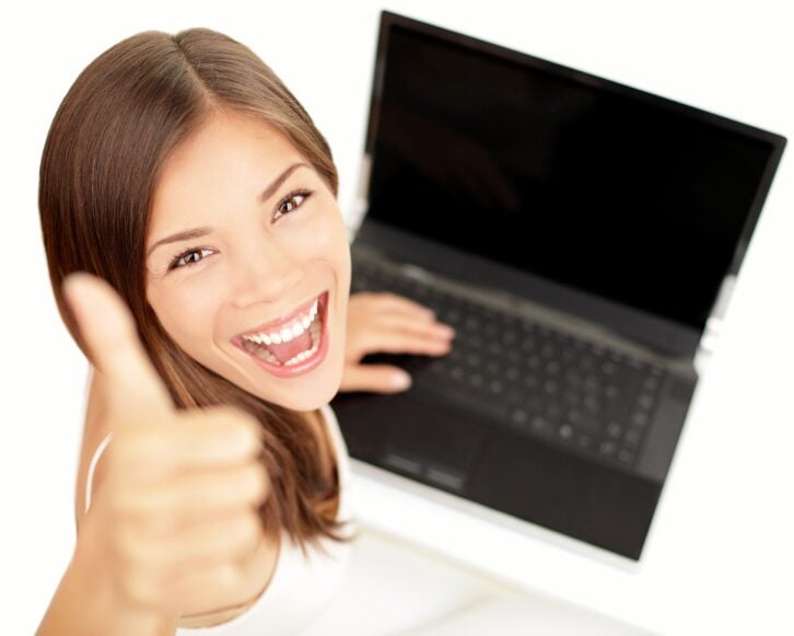 happy woman giving thumbs up sitting at laptop with excited face expression
