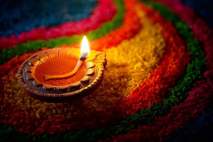 traditional diya lamp lit on colorful rangoli