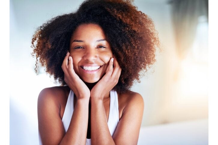 Woman smiling holding her face with freshly cleaned skin