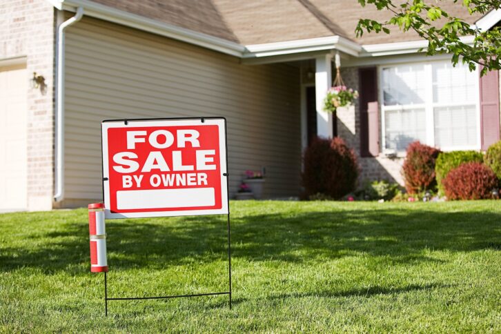 home with 'For Sale By Owner' sign in front yard