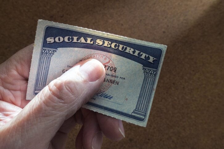 Hand holding social security card with thumb over the number