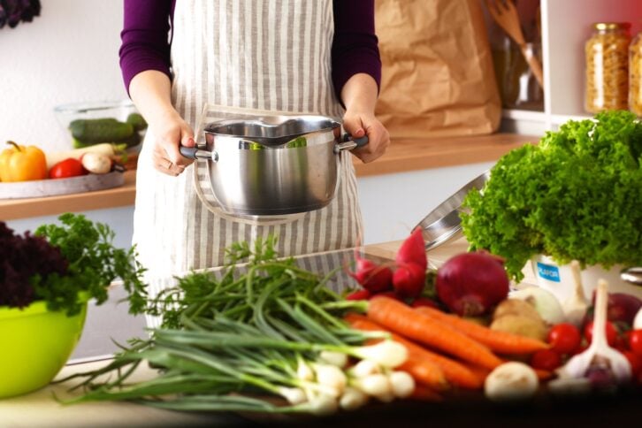 women in kitchen cooking with vegetables