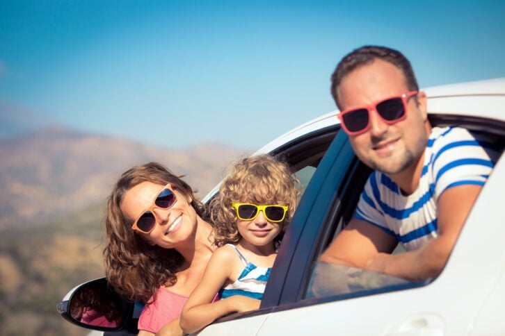 father, mother, and child hanging out of car windows