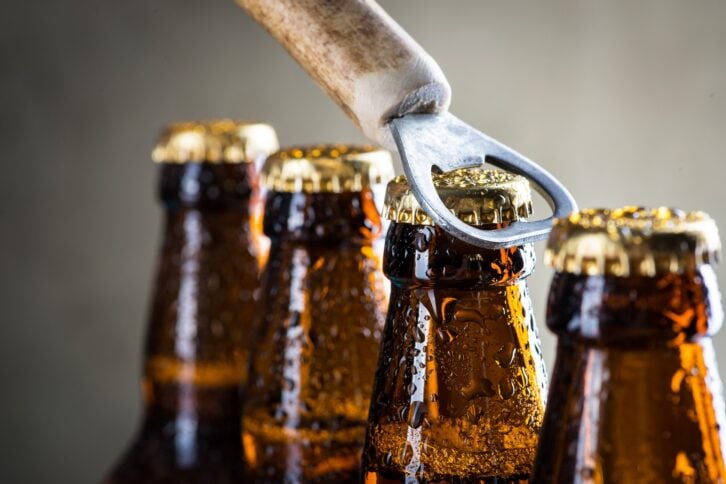 brown ice cold beer bottles with water drops and old opener
