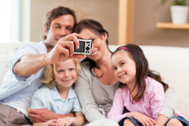 happy father taking a picture of his family in a living room