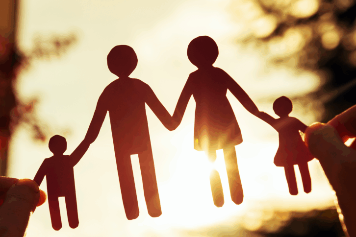 Paper cutout of family facing a sunset