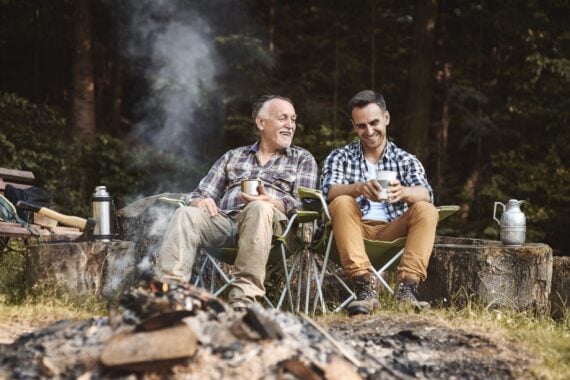 father and adult son bonding while camping in forest