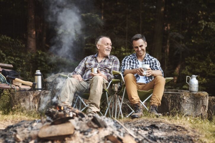 father and adult son bonding while camping in forest
