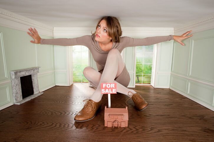 young woman in small house with model of house for sale