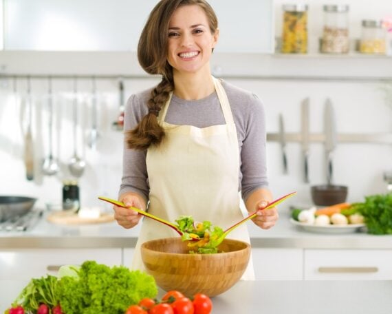 happy young housewife mixing vegetable salad