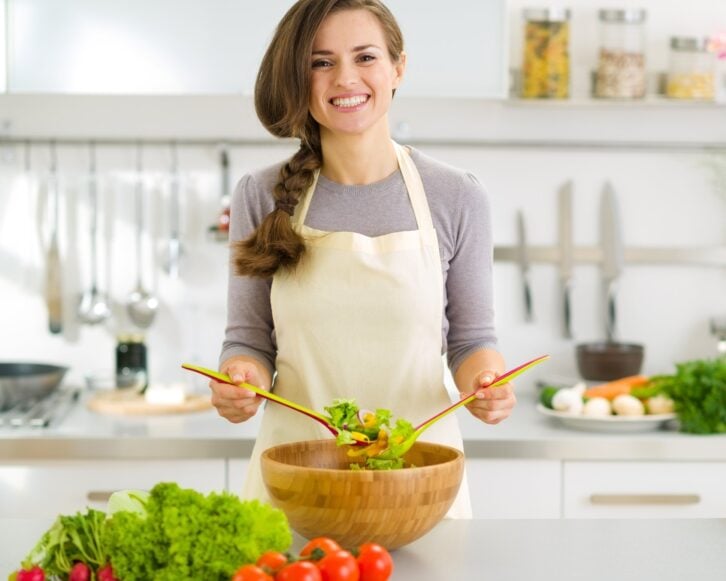happy young housewife mixing vegetable salad