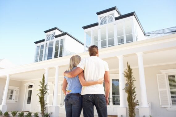 young couple standing outside dream home