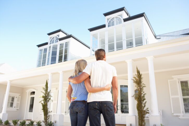 young couple standing outside dream home