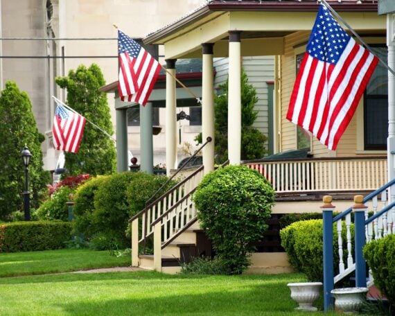 American flags flying proudly on front porches of a small town during a holiday