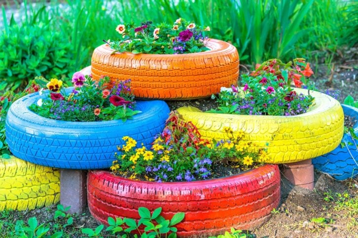 old tires that are painted in assorted colors and used for a flower planter
