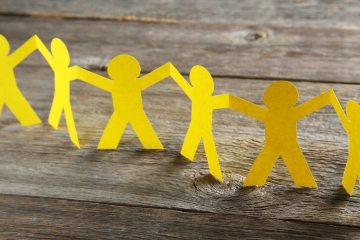 yellow paper people on gray wooden background
