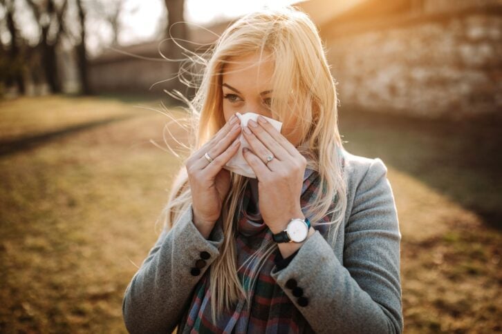 woman outside during fall blowing her nose