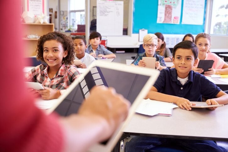 teacher using tablet computer in elementary school lesson
