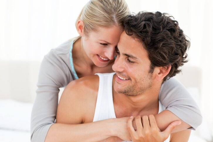 couple hugging on their bed at home