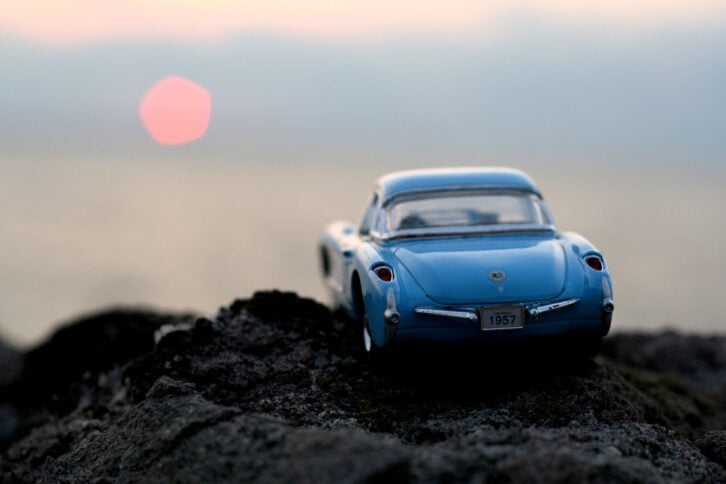 toy corvette on a rock with the sunset in the background
