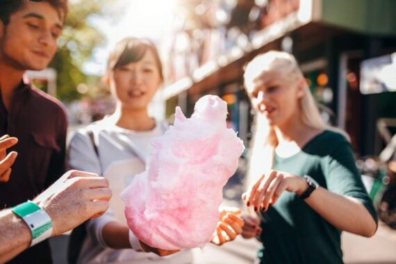 young people sharing cotton candy at amusement park