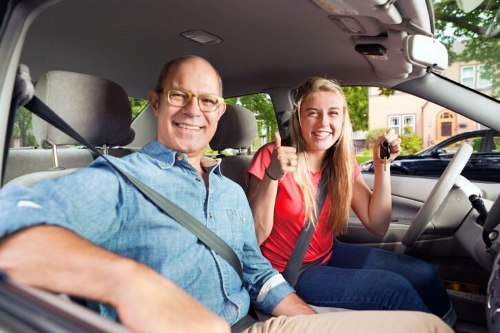 parent driving instructor and happy teenage student driver in car