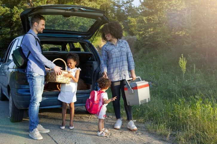 happy family unloading luggage from the car for summer vacation
