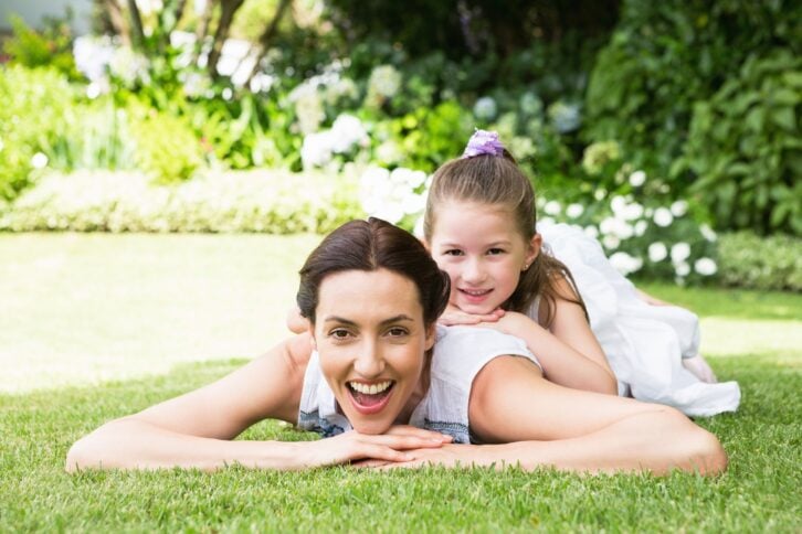 mother and daughter laying on grass in yard