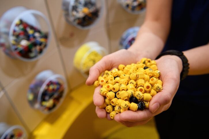 sales assistant holds a handful of Lego figure heads during an opening party event at the new flagship Lego store on November 16, 2016 in London, England
