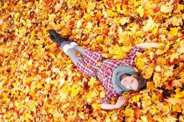 woman falling into autumn leaves