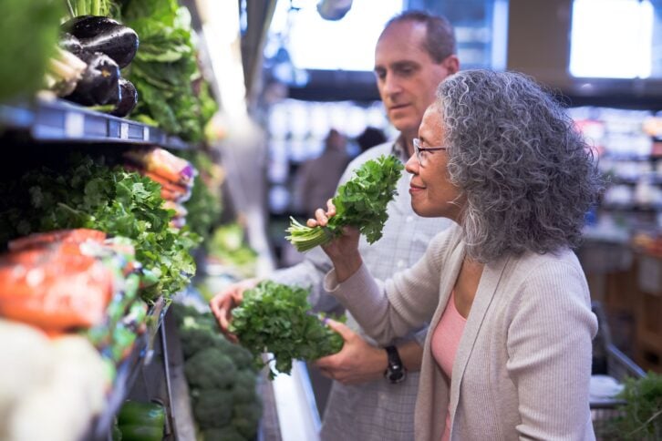 senior couple selecting fresh herbs at the grocery store