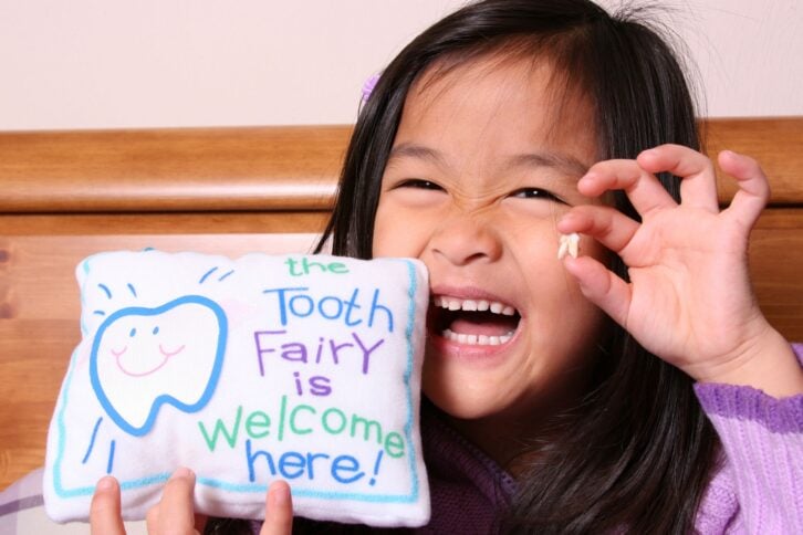Chinese little girl holding up her tooth