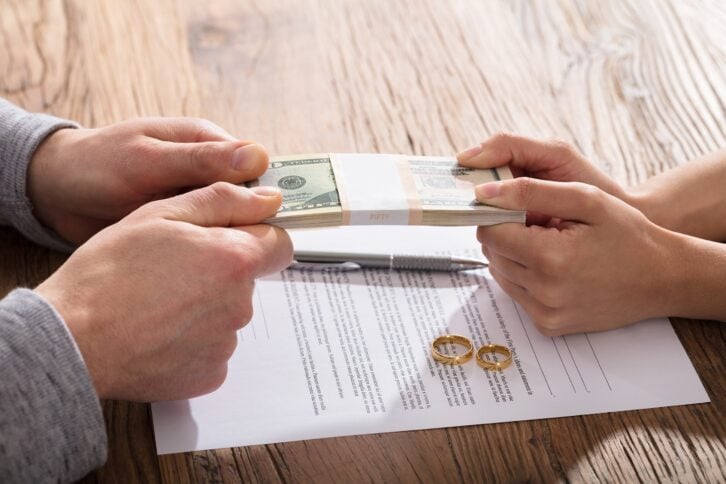 couple fighting for money over the divorce agreement with gold wedding rings