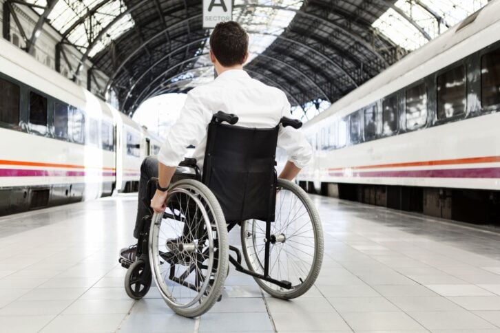 man win wheelchair on train platform with train on either side