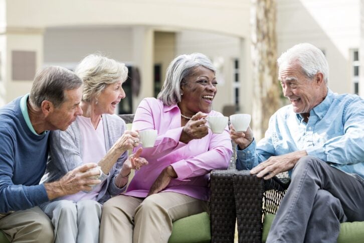 multiracial senior friends outdoors drinking coffee