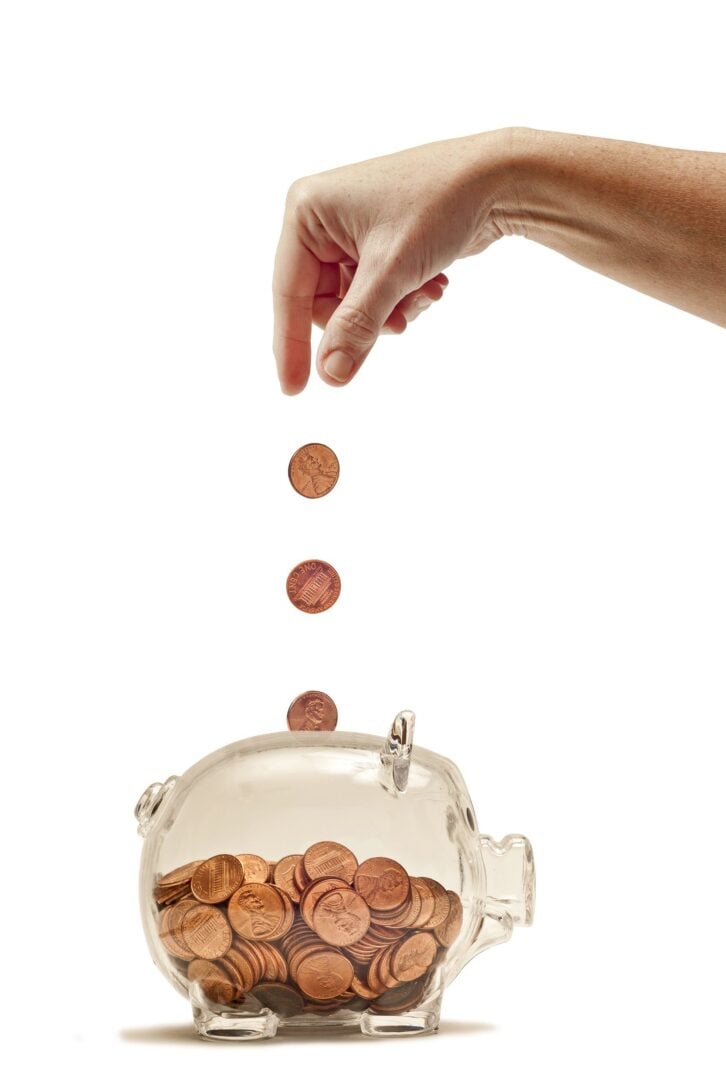 hand feeding piggy bank with pennies
