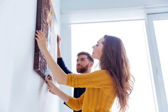 Happy couple hanging art on a wall at home