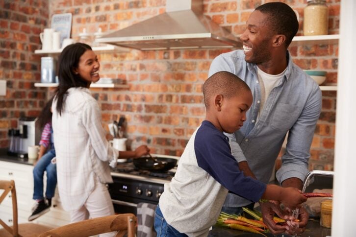 African American children helping parents to prepare meal in kitchen