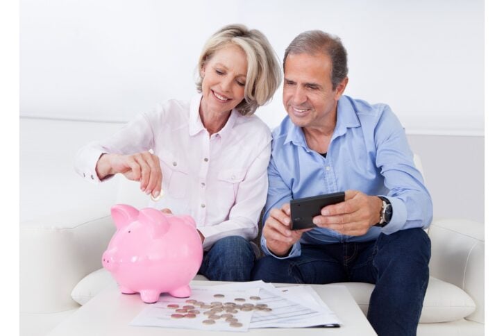 Happy older couple putting coins in a piggy bank