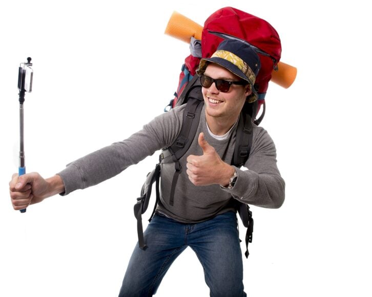 young attractive backpacker tourist taking selfie photo with stick carrying backpack