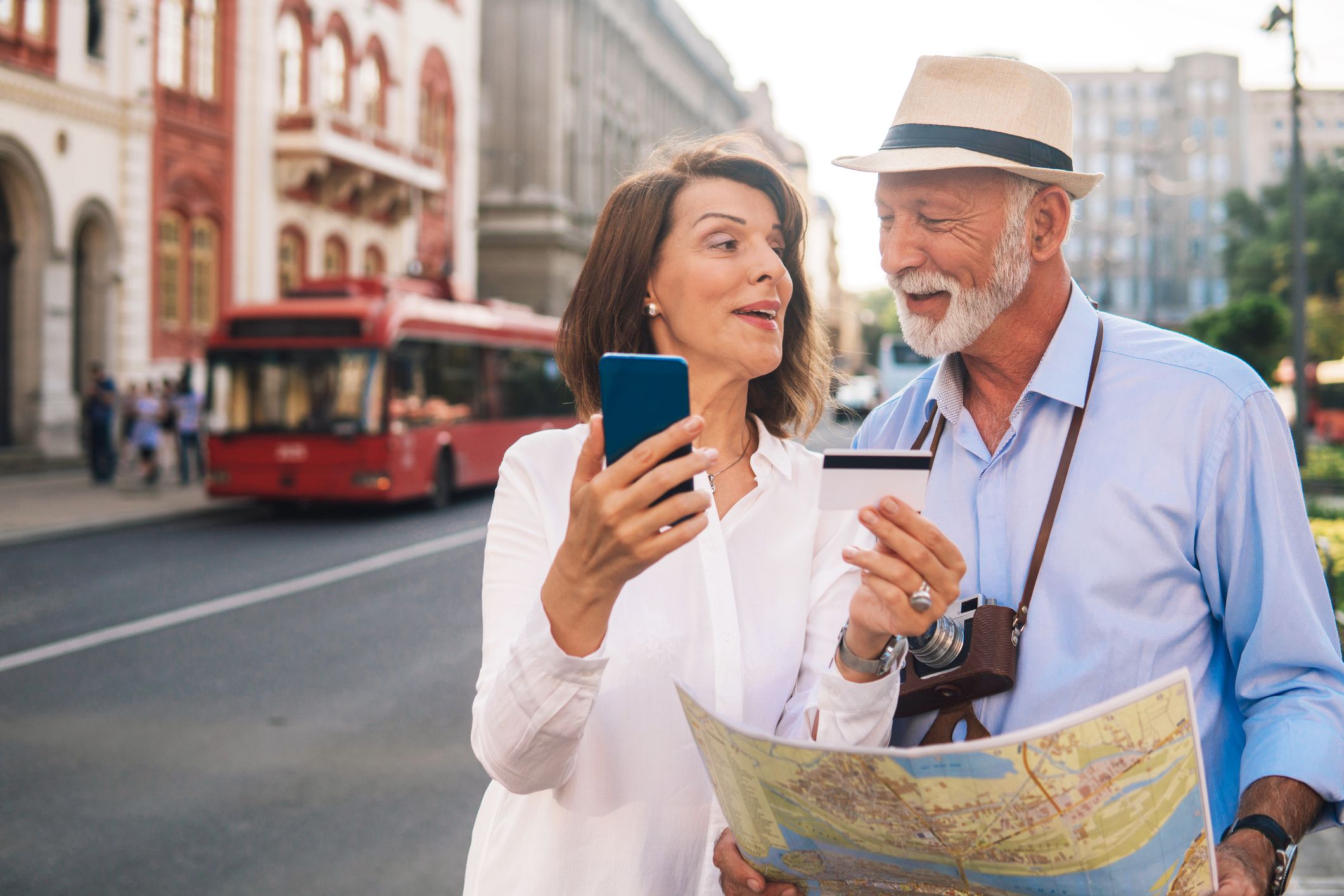 older couple smiling looking at card and map in travel destination
