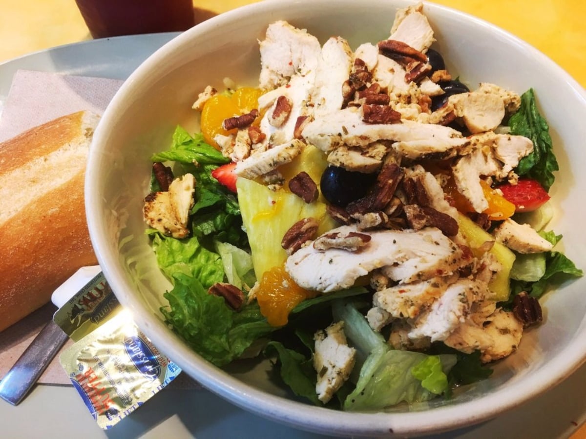 A bowl of salad with chicken and nuts