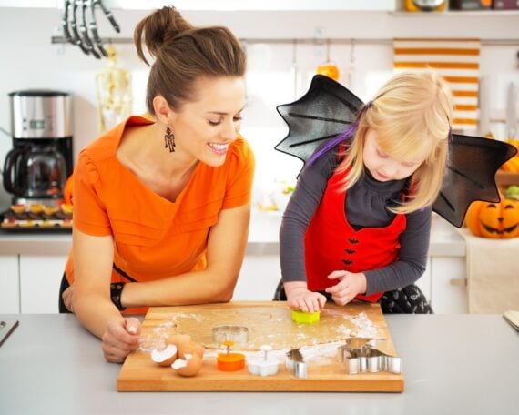 Halloween dressed girl with young mother in decorated kitchen