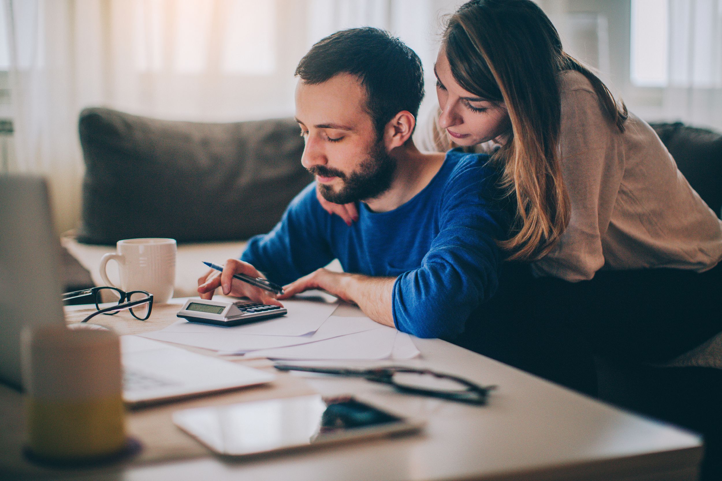 couple doing finances at desk with laptop and electronics